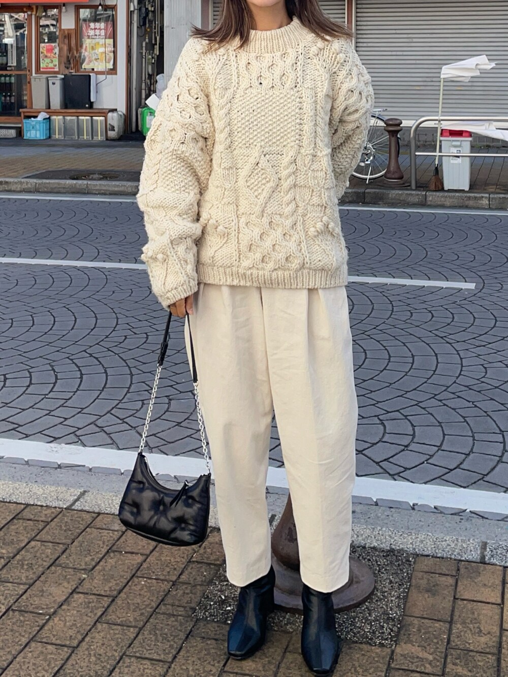 ホワイト系のニット/セーター、ホワイト系のその他パンツ、ブラック系のブーツを着用したレディースの冬コーディネートの2枚目の写真