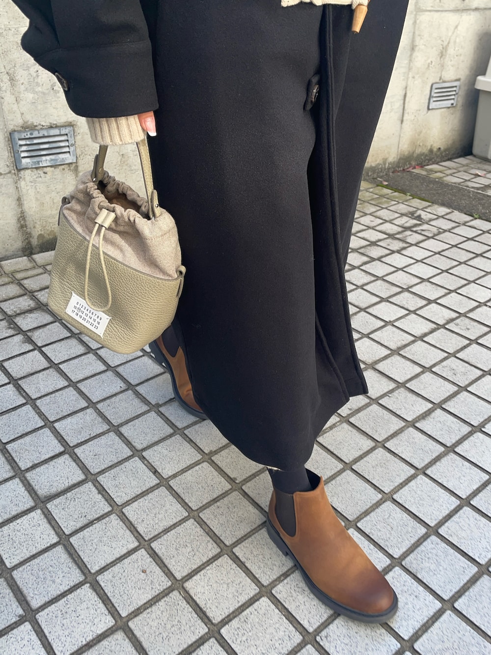 ベージュ系のショルダーバッグ、ブラック系のダッフルコート、ブラウン系のブーツを着用したレディースの秋コーディネートの5枚目の写真