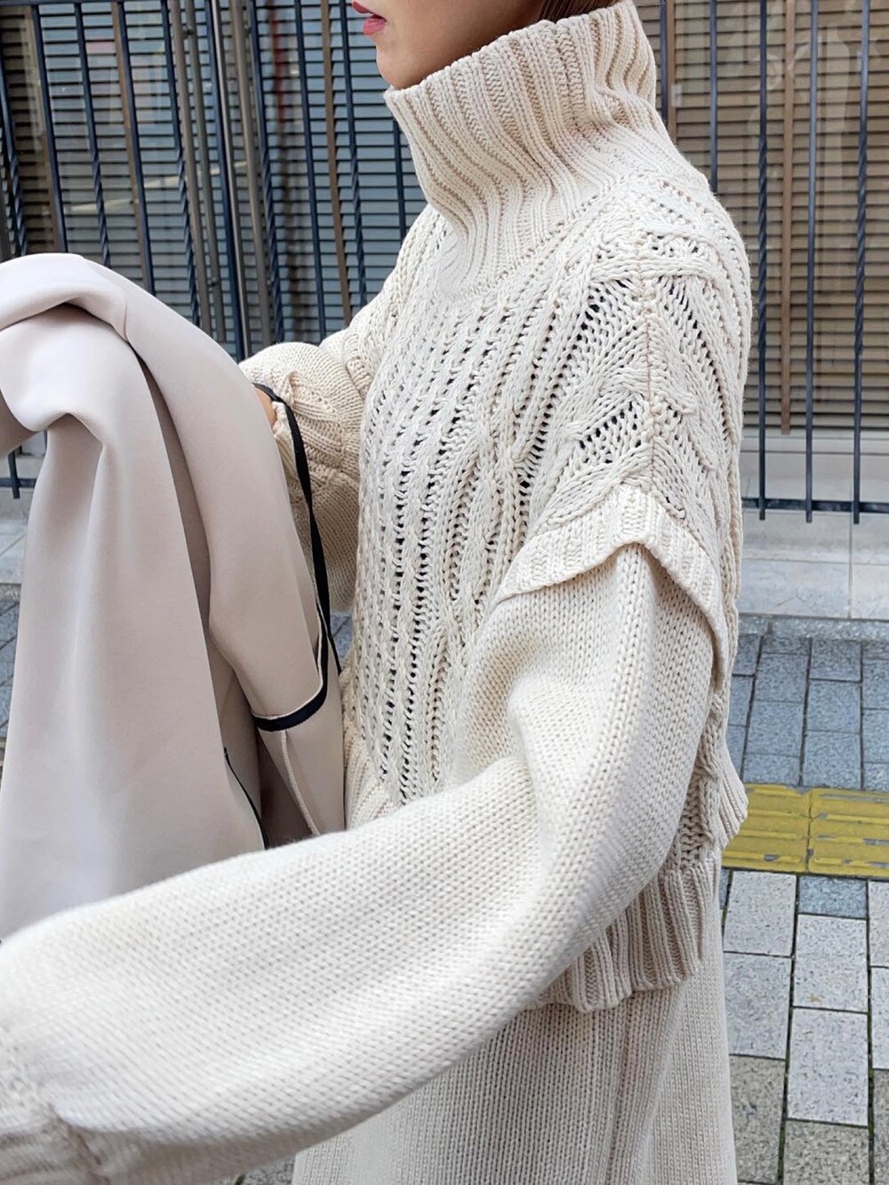 ブラック系のブーツ、ホワイト系のバッグ、ゴールド系のリングを着用したレディースの秋コーディネートの3枚目の写真