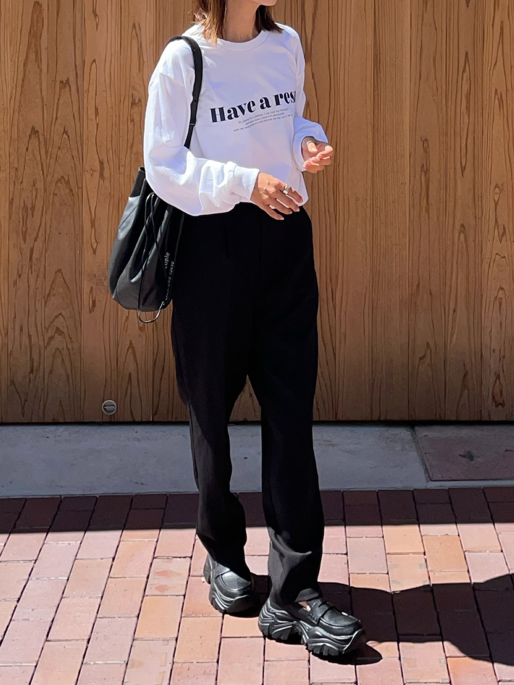 ブラック系のバッグ、ブラック系のスニーカー、ホワイト系のTシャツ/カットソーを着用したレディースの夏コーディネートの2枚目の写真