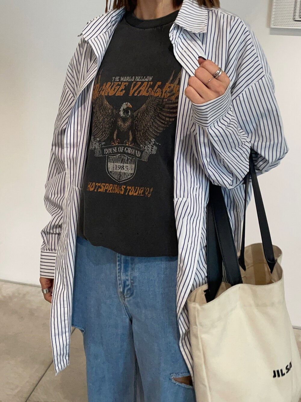 ホワイト系のトートバッグ、ブルー系のデニムパンツ、ブラック系のTシャツ/カットソーを着用したレディースの夏コーディネートの2枚目の写真