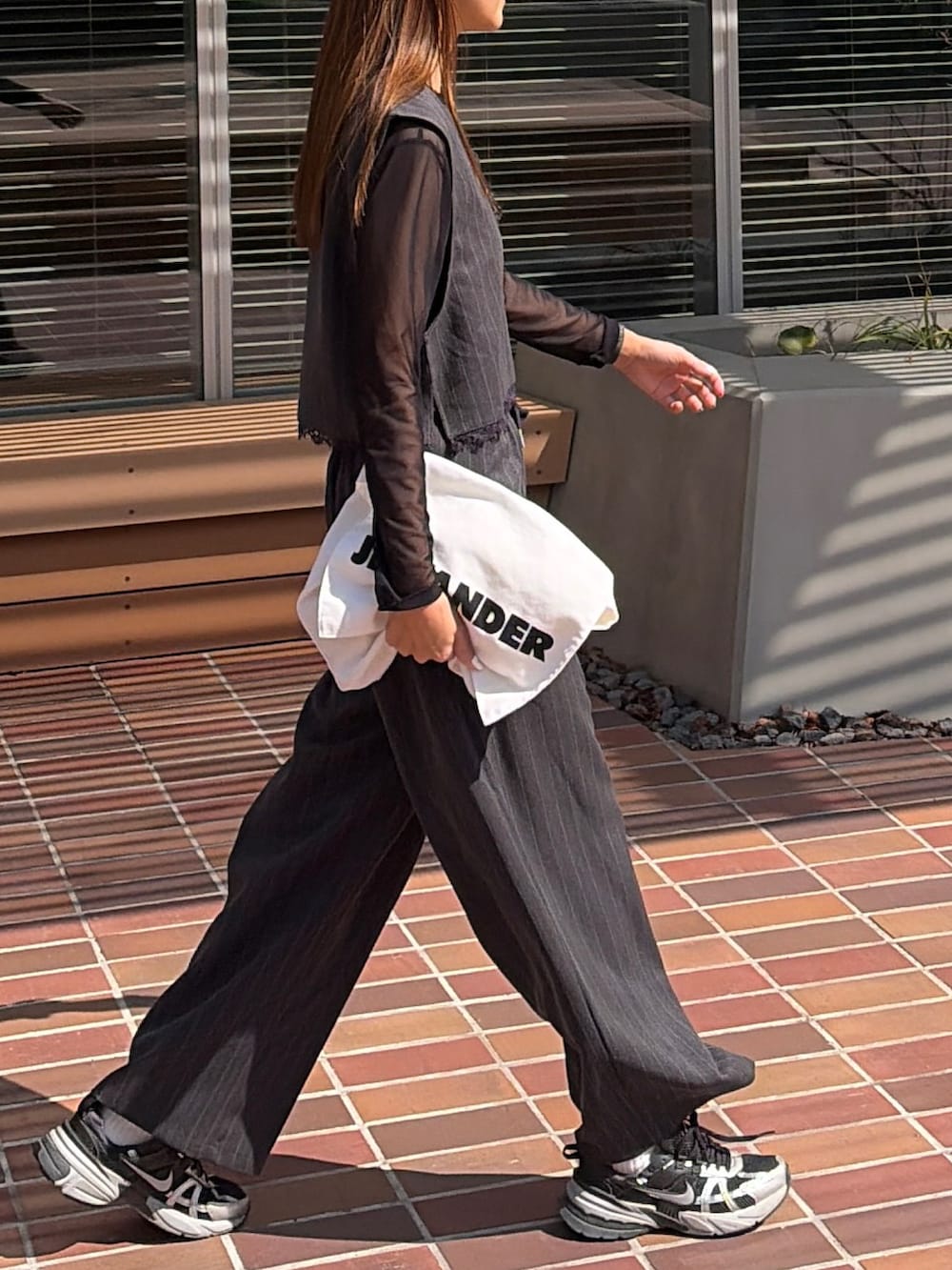 グレー系のベスト、グレー系のスラックスを着用したレディースの春コーディネートの3枚目の写真