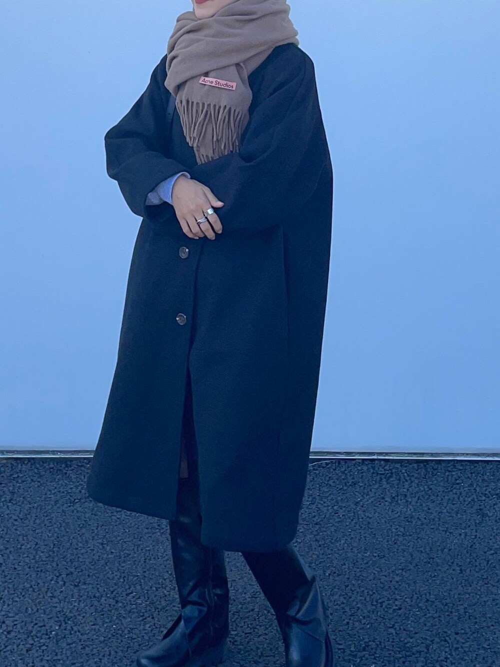 ブラック系のバッグ、ブラック系のブーツ、ブラック系のステンカラーコートを着用したレディースの秋コーディネートの2枚目の写真