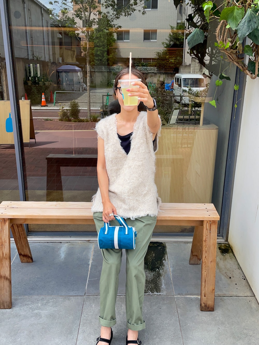 グリーン系のチノパンツ、ホワイト系のベスト、ブルー系のショルダーバッグを着用したレディースの秋コーディネートの2枚目の写真