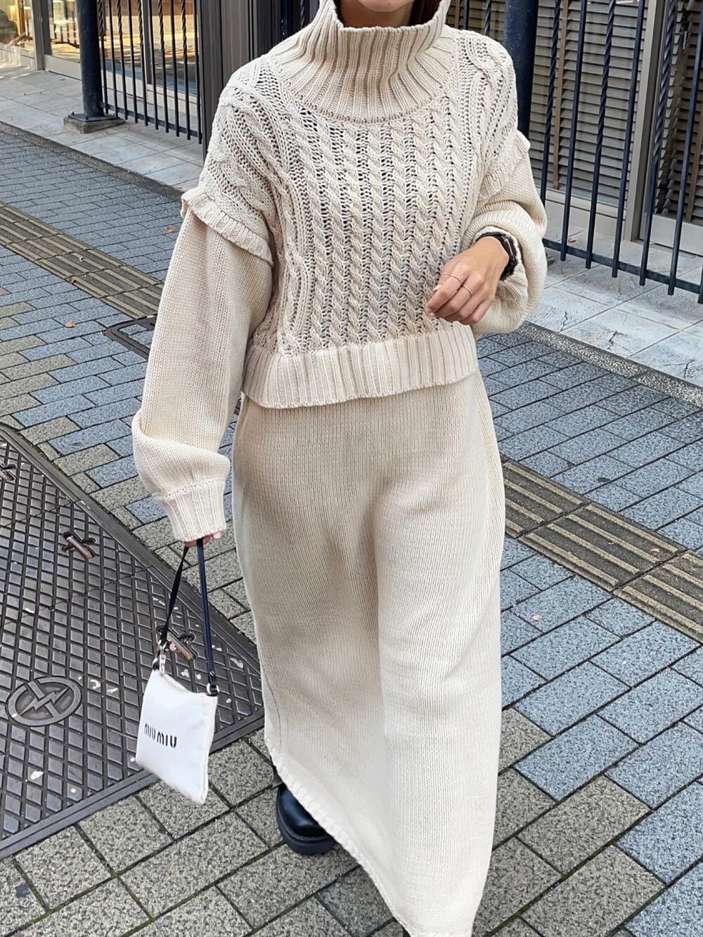 ブラック系のブーツ、ホワイト系のバッグ、ゴールド系のリングを着用したレディースの秋コーディネートの2枚目の写真