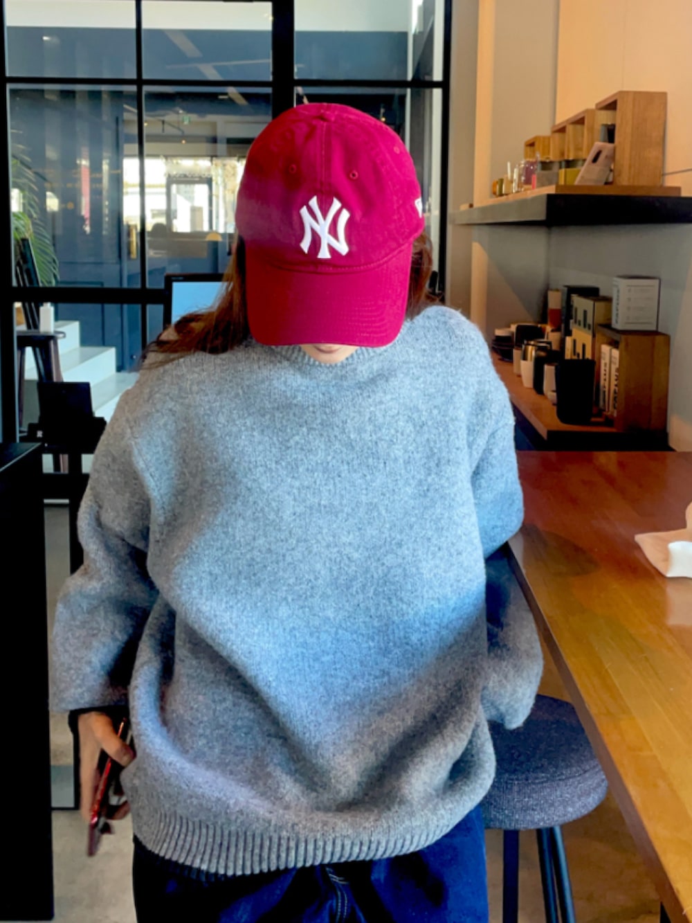 グレー系のニット/セーター、レッド系のキャップを着用したレディースの冬コーディネートの2枚目の写真