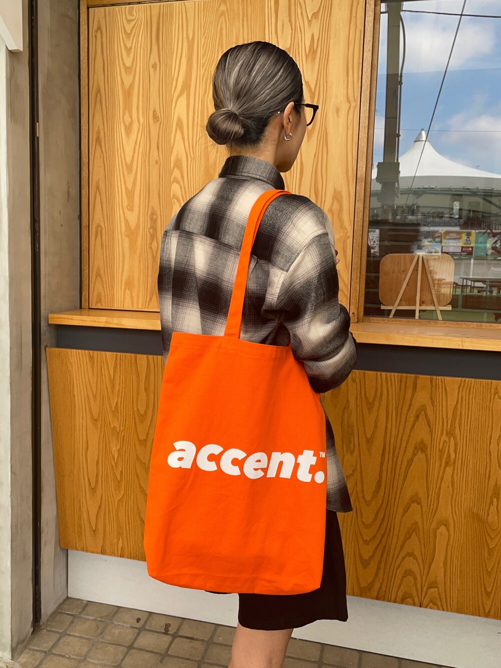 グレー系のスニーカー、ブラック系のその他パンツ、オレンジ系のトートバッグを着用したレディースの秋コーディネートの2枚目の写真