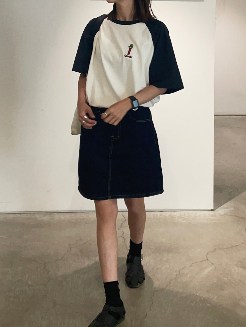 ブラック系のサンダル、ホワイト系のトートバッグ、ブラック系のTシャツ/カットソーを着用したレディースの夏コーディネートの2枚目の写真