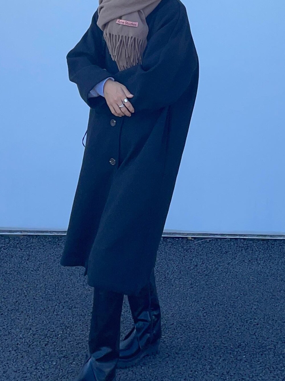 ブラック系のバッグ、ブラック系のブーツ、ブラック系のステンカラーコートを着用したレディースの秋コーディネートの3枚目の写真