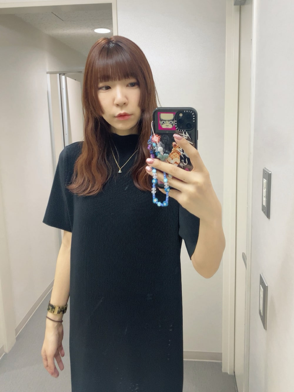ブラック系のワンピース、ホワイト系のスニーカー、ブルー系のネックレスを着用したレディースの春コーディネートの2枚目の写真