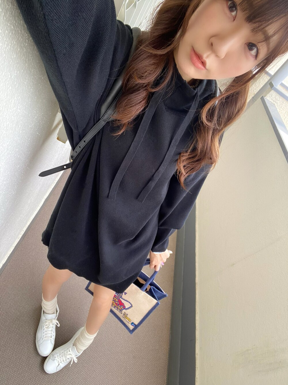 ブラック系のワンピース、ブラウン系のバックパック/リュック、ホワイト系のスニーカーを着用したレディースの春コーディネートの2枚目の写真