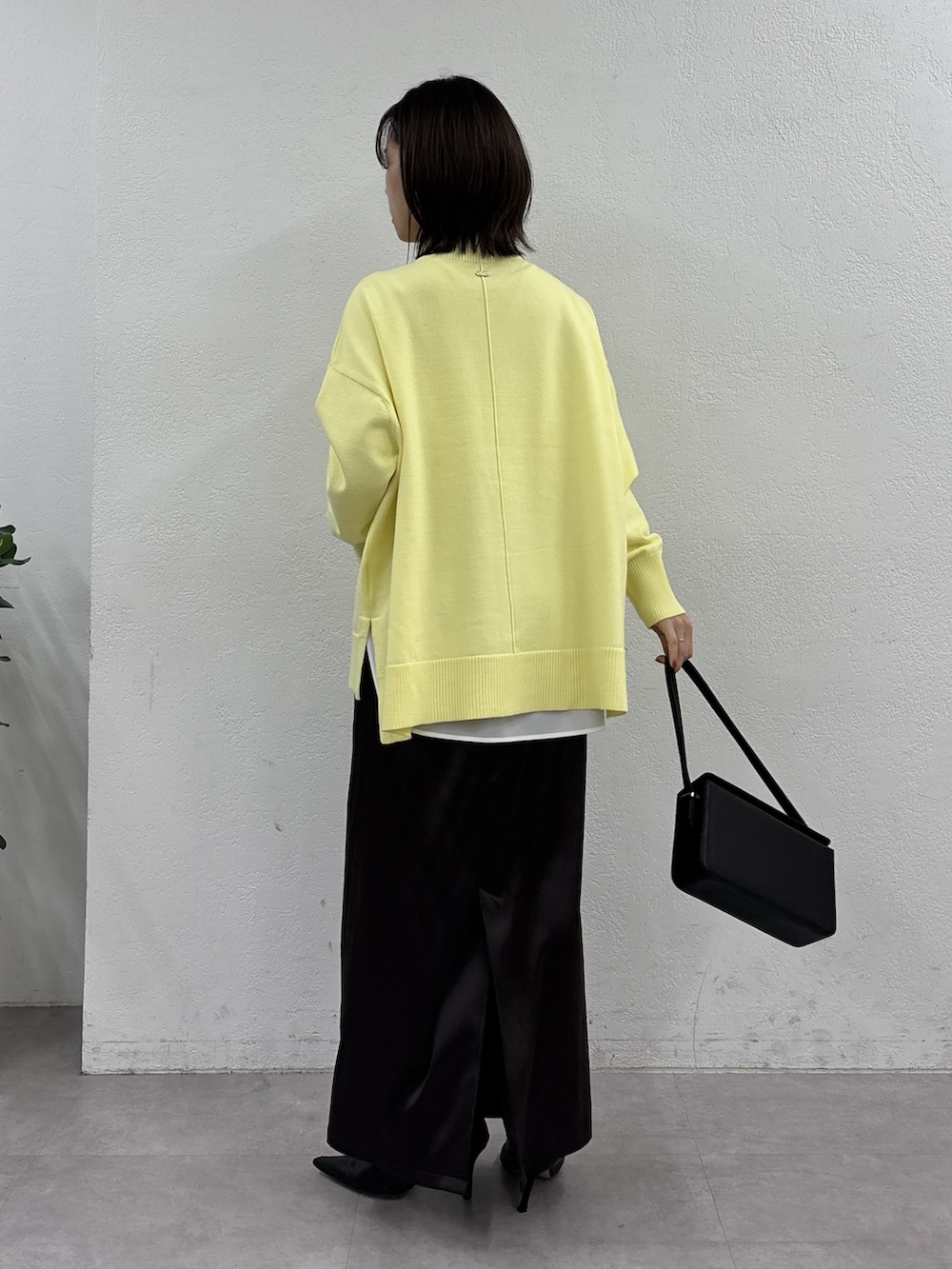 イエロー系のニット/セーター、ホワイト系のシャツ/ブラウス、ブラウン系のスカートを着用したレディースの秋コーディネートの3枚目の写真