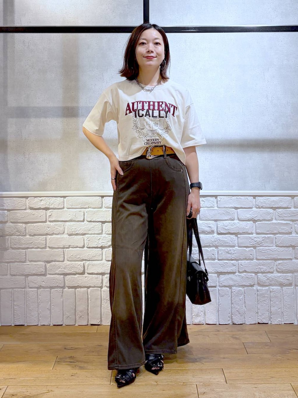 ブラウン系のデニムパンツ、ホワイト系のTシャツ/カットソー、ブラック系のサンダルを着用したレディースの夏コーディネートの4枚目の写真