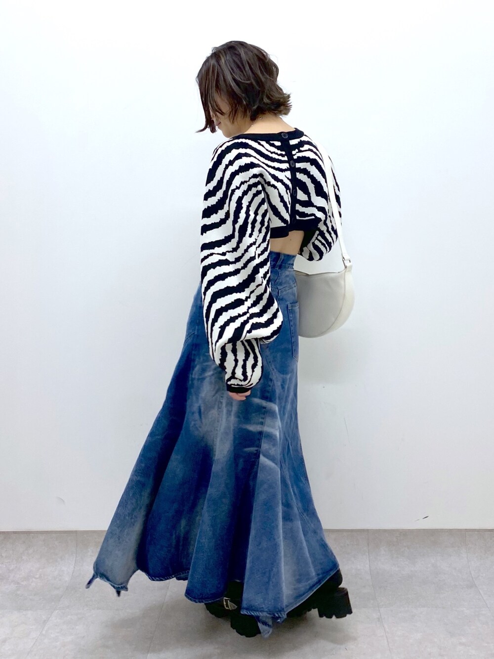 ブルー系のスカート、ブラック系のトップス、ホワイト系のショルダーバッグを着用したレディースの冬コーディネートの3枚目の写真