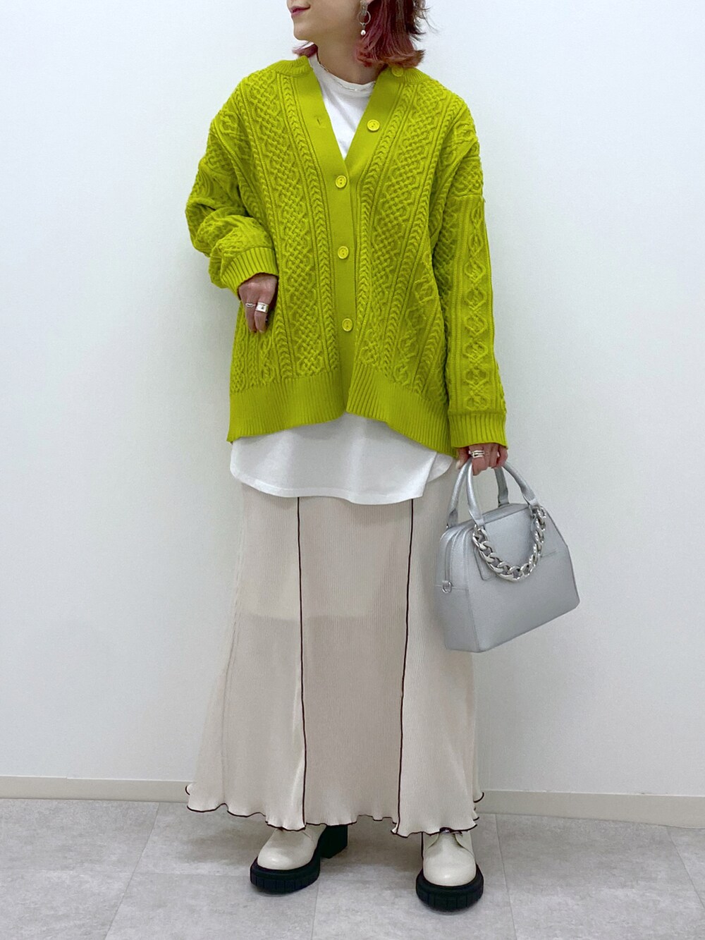 イエロー系のニット/セーター、ホワイト系のスカート、ホワイト系のローファーを着用したレディースの冬コーディネートの5枚目の写真