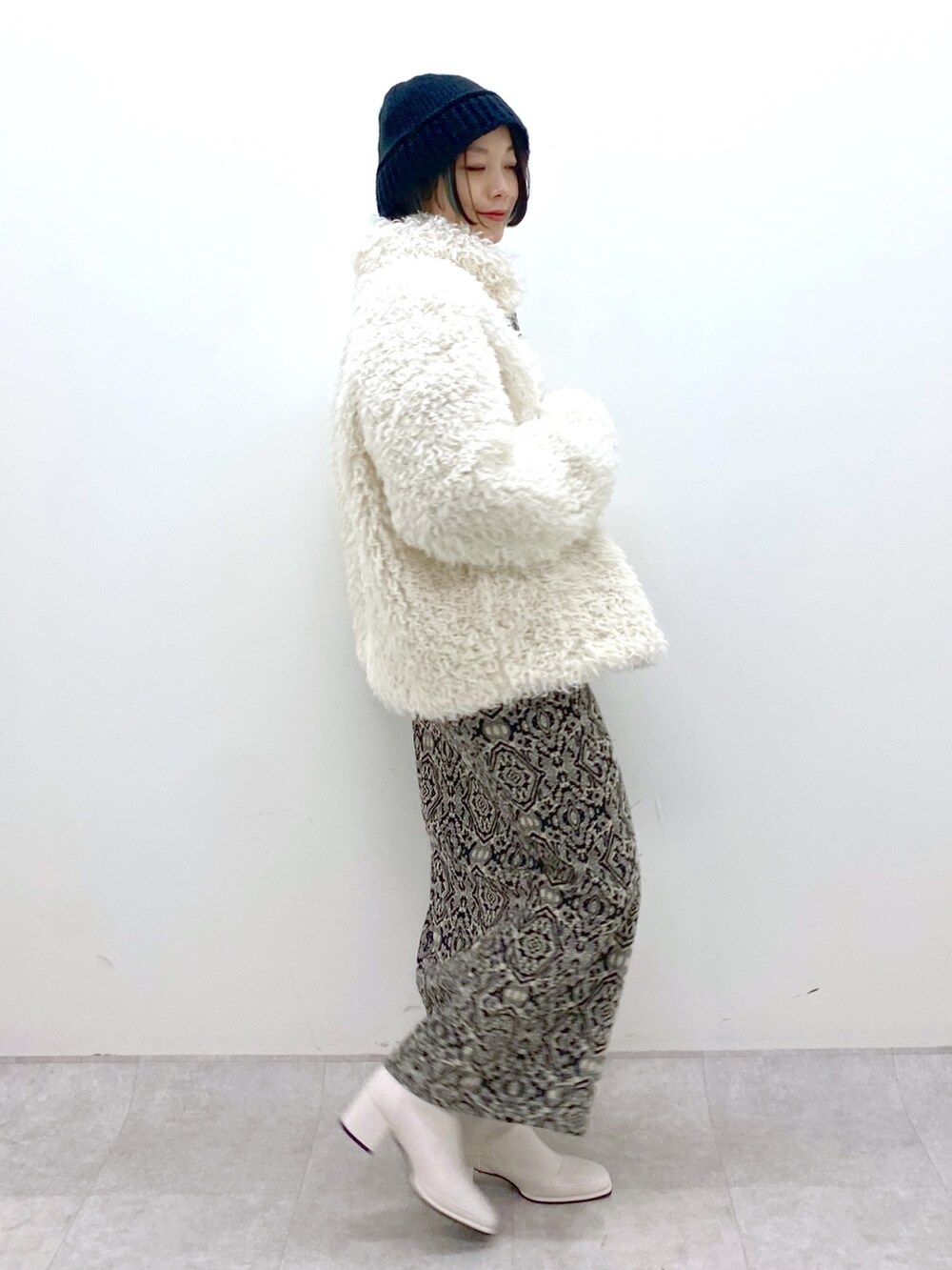 ブラック系のスカート、ブルー系のトップス、ホワイト系のシューズを着用したレディースの秋コーディネートの2枚目の写真