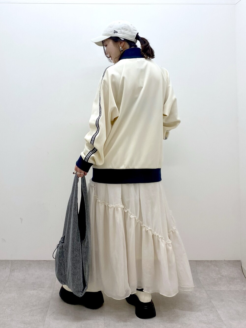 ホワイト系のセットアップ、ブラック系のトートバッグ、ホワイト系のスカートを着用したレディースの冬コーディネートの5枚目の写真