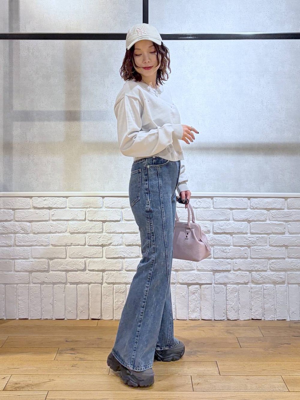 グレー系のスニーカー、ブルー系のデニムパンツ、ピンク系のハンドバッグを着用したレディースの冬コーディネートの7枚目の写真