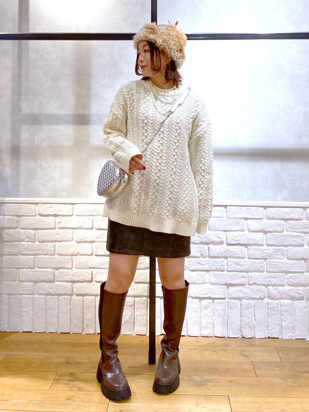 ホワイト系のニット/セーター、ブラック系のスカート、ブラウン系のブーツを着用したレディースの冬コーディネートの9枚目の写真