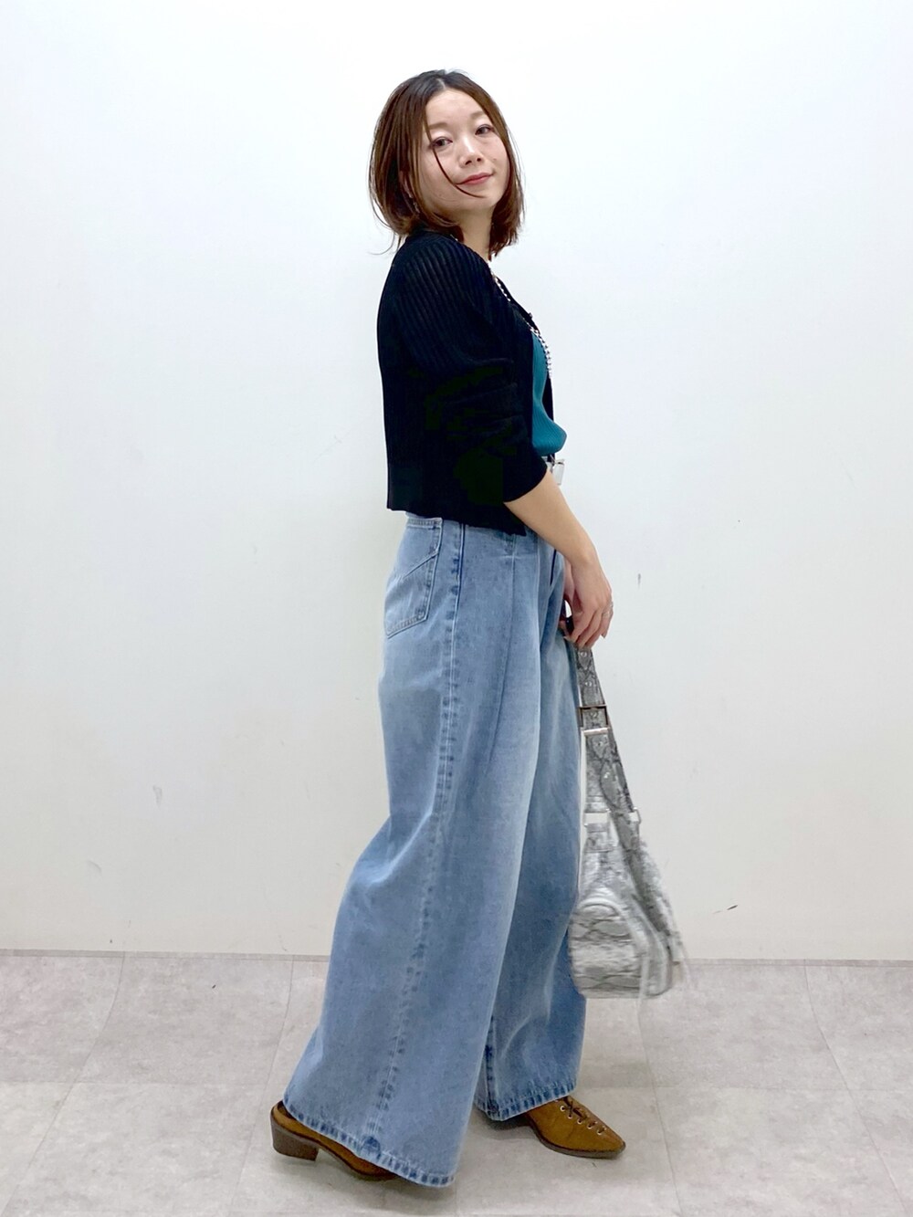 ブラック系のカーディガン/ボレロ、グリーン系のタンクトップ、ブルー系のデニムパンツを着用したレディースの春コーディネートの7枚目の写真