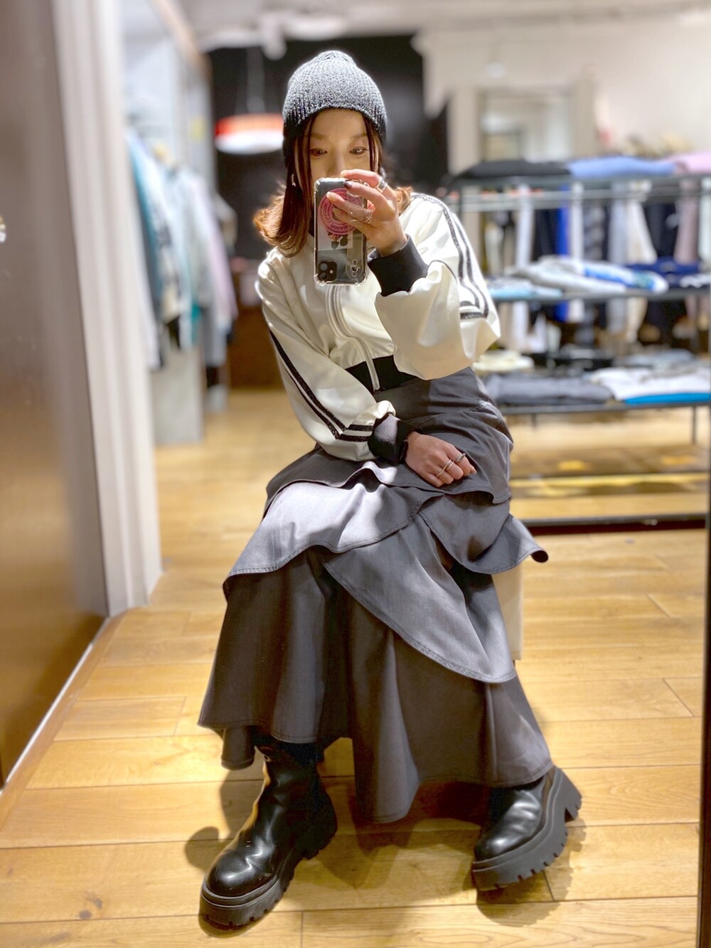 グレー系のスカート、ホワイト系のジャージ、ブラック系のブーツを着用したレディースの冬コーディネートの2枚目の写真