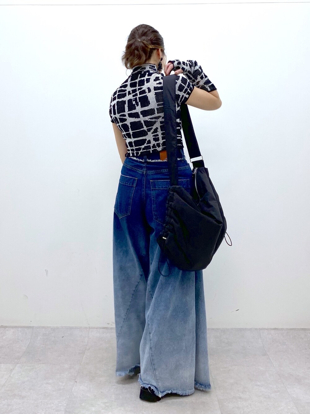 ブルー系のデニムパンツ、ブラック系のニット/セーター、ブラック系のショルダーバッグを着用したレディースの夏コーディネートの4枚目の写真