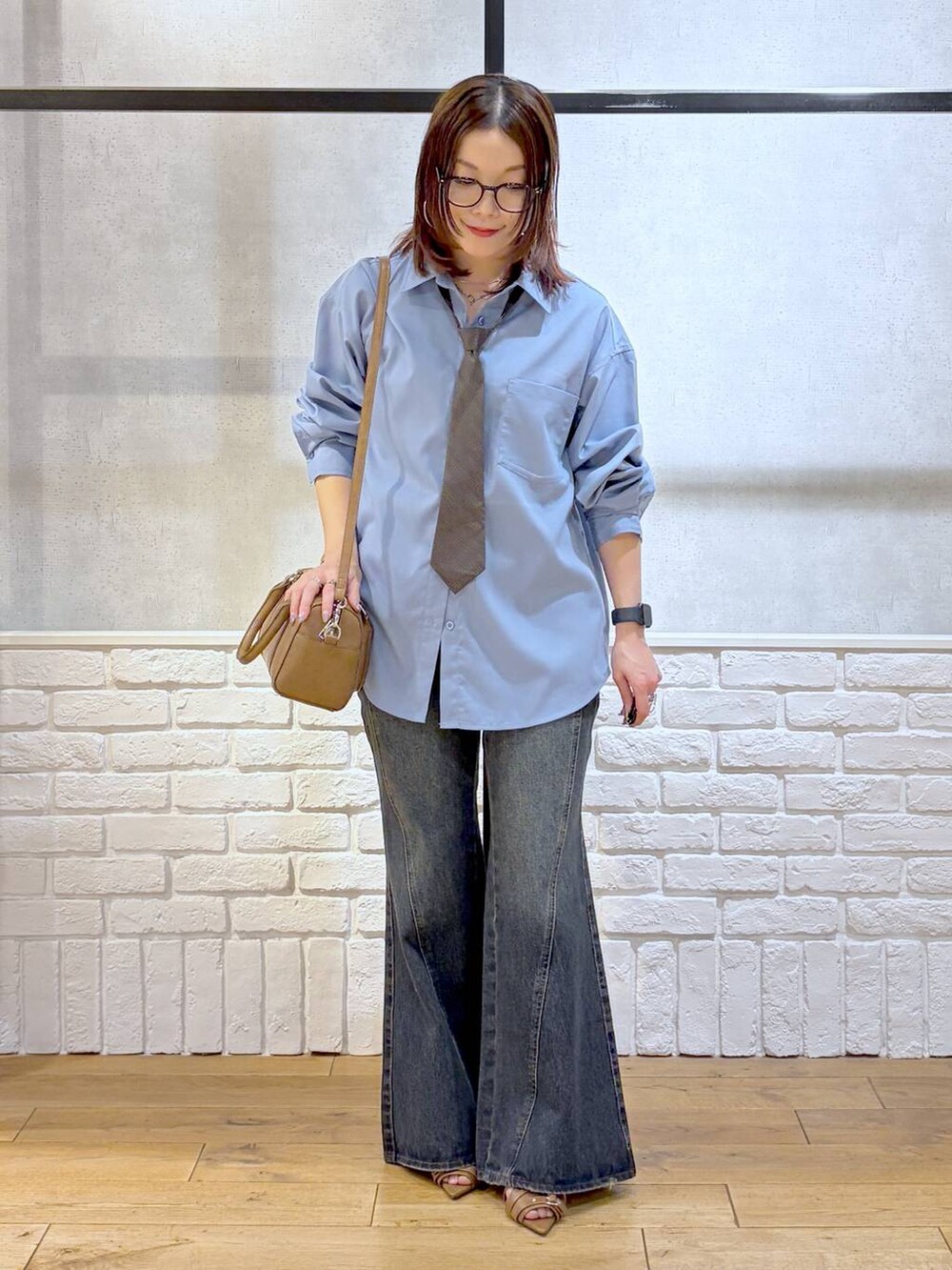 ブルー系のデニムパンツ、ブラウン系のボストンバッグ、イエロー系のサンダルを着用したレディースの春コーディネートの8枚目の写真