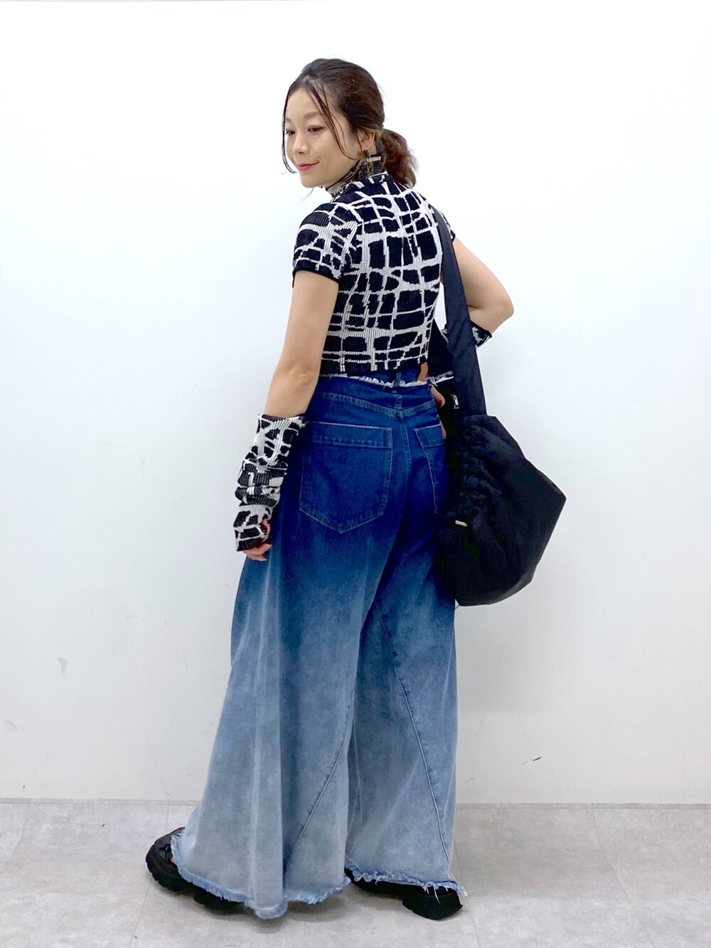 ブルー系のデニムパンツ、ブラック系のニット/セーター、ブラック系のショルダーバッグを着用したレディースの夏コーディネートの6枚目の写真