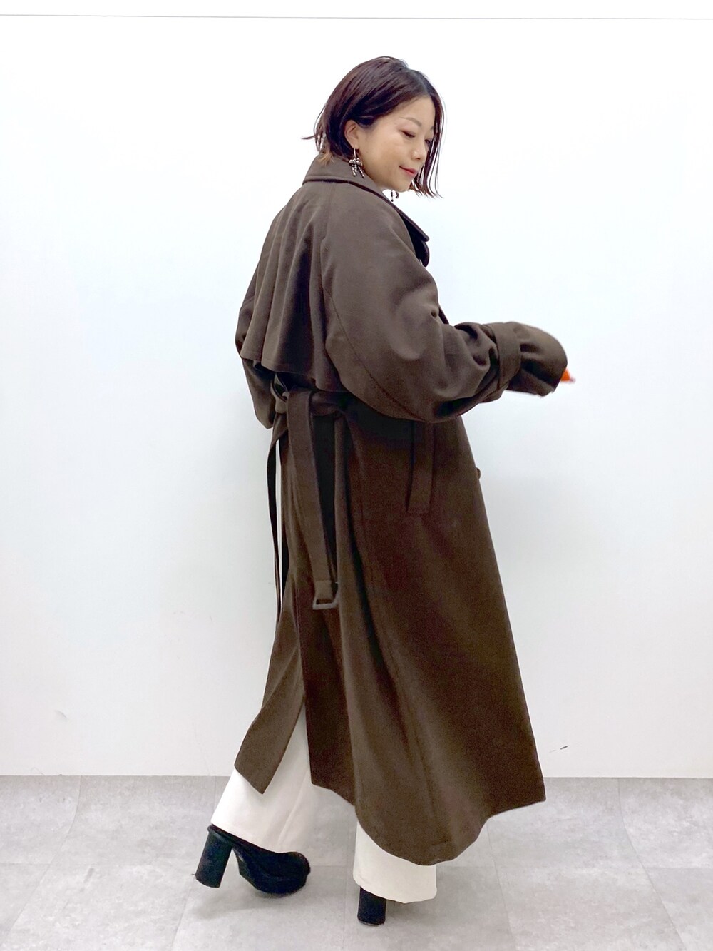 ブラック系のトップス、オレンジ系のトップス、ホワイト系のパンツを着用したレディースの秋コーディネートの2枚目の写真