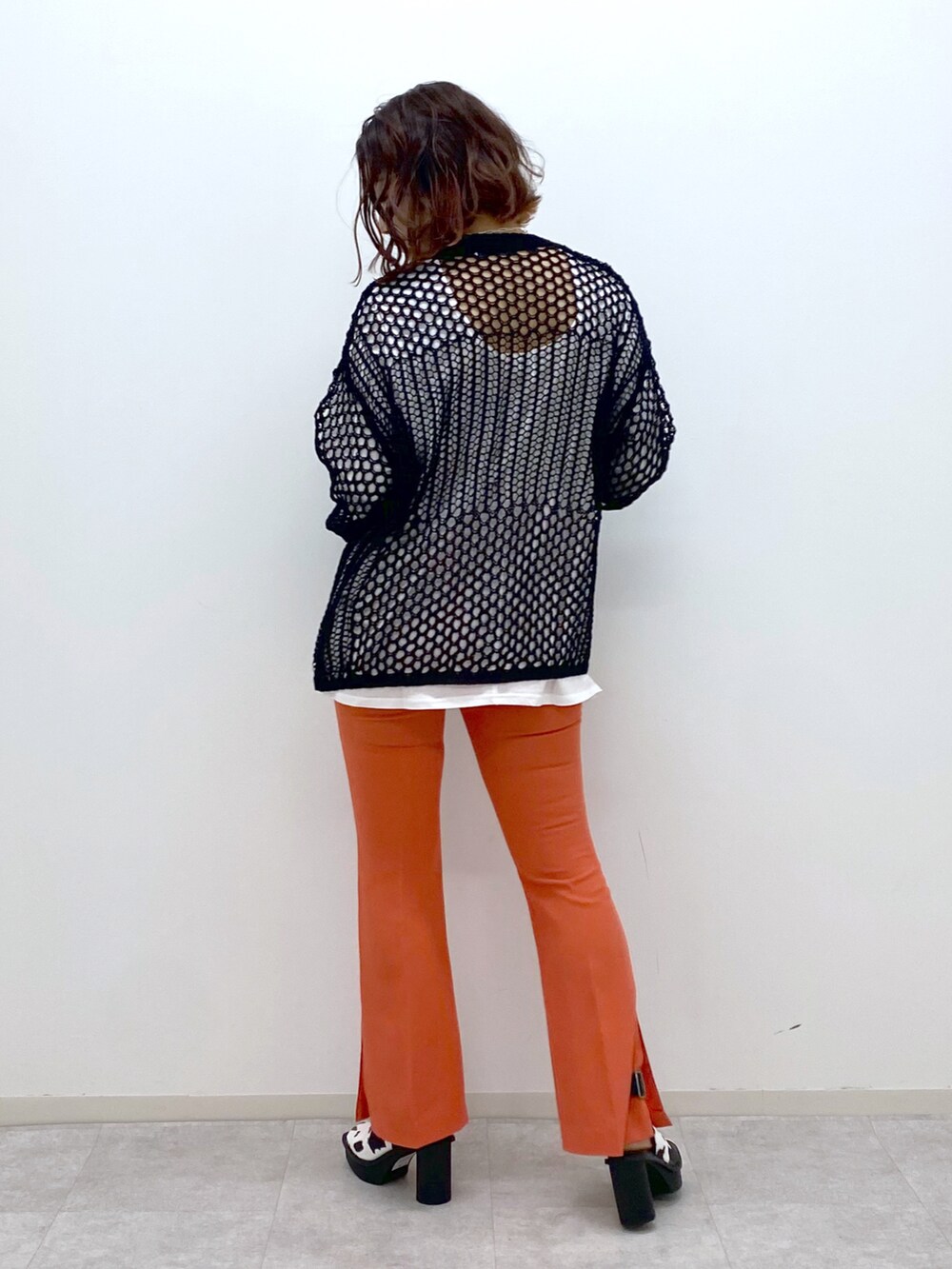オレンジ系のその他パンツ、ホワイト系のサンダル、ブラック系のニット/セーターを着用したレディースの春コーディネートの3枚目の写真
