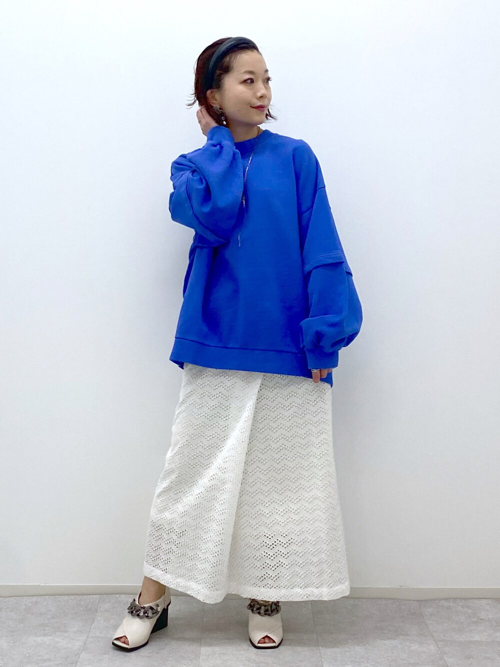 ブルー系のスウェット、ホワイト系のスカート、ホワイト系のパンプスを着用したレディースの冬コーディネートの2枚目の写真