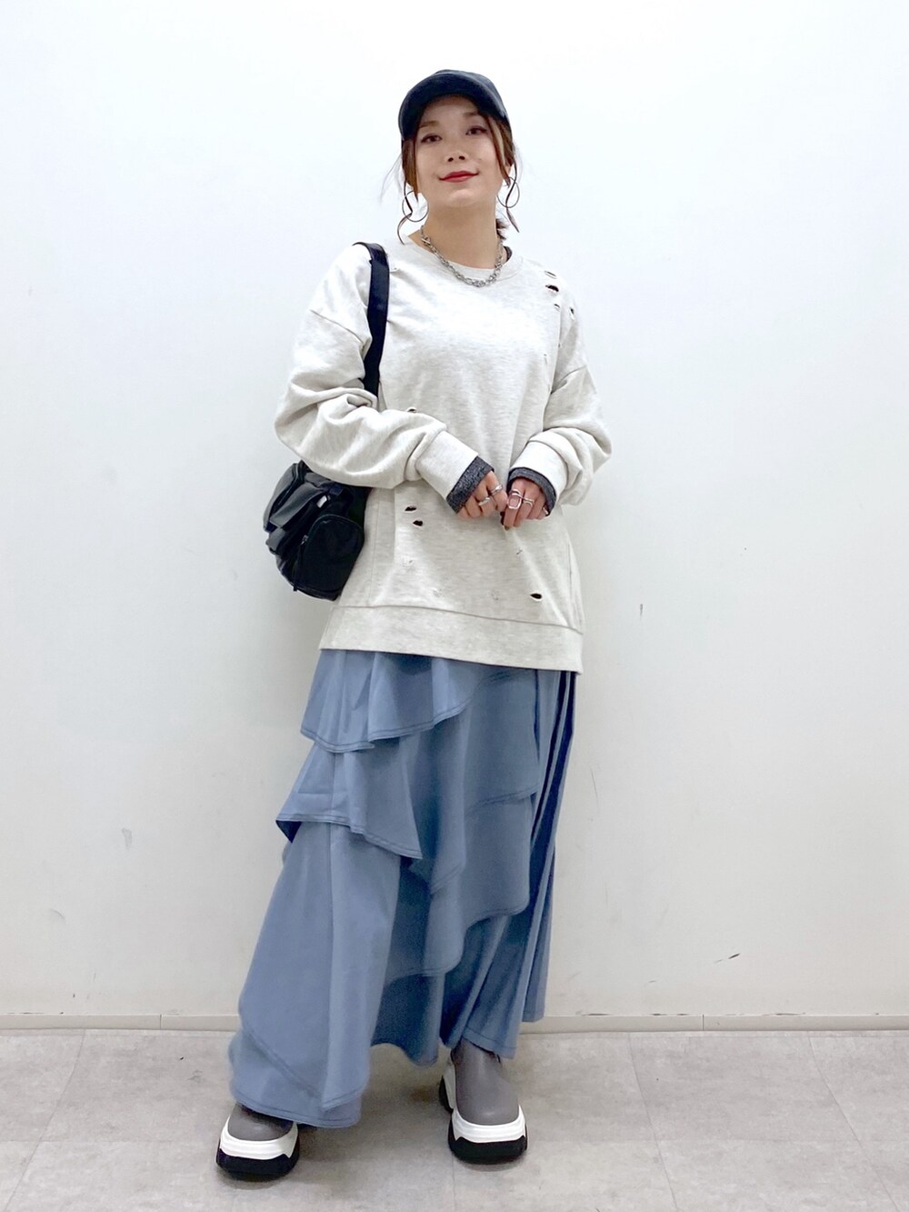 ブラック系のショルダーバッグ、ブルー系のスカート、グレー系のブーツを着用したレディースの秋コーディネートの9枚目の写真