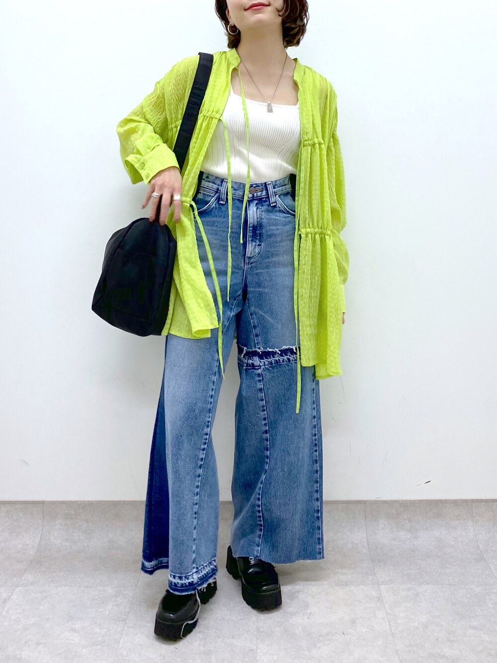 ブルー系のデニムパンツ、ホワイト系のトップス、イエロー系のトップスを着用したレディースの春コーディネートの5枚目の写真