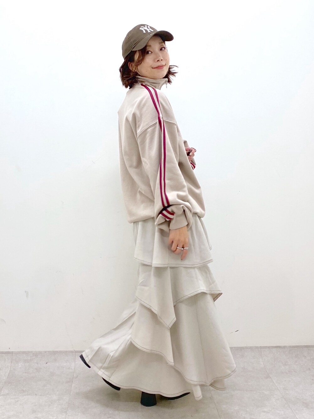 ベージュ系のスウェット、グレー系のスカート、ブラック系のブーツを着用したレディースの秋コーディネートの7枚目の写真