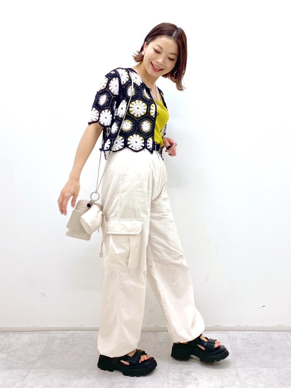 ホワイト系のカーゴパンツ、イエロー系のタンクトップ、ブラック系のトップスを着用したレディースの夏コーディネートの2枚目の写真