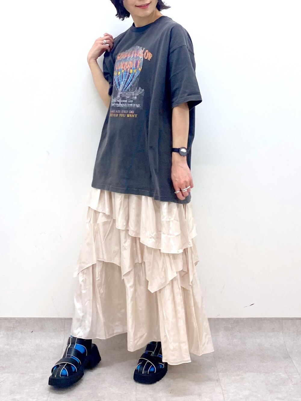 グレー系のTシャツ/カットソー、ホワイト系のスカート、ブラック系のサンダルを着用したレディースの春コーディネートの4枚目の写真