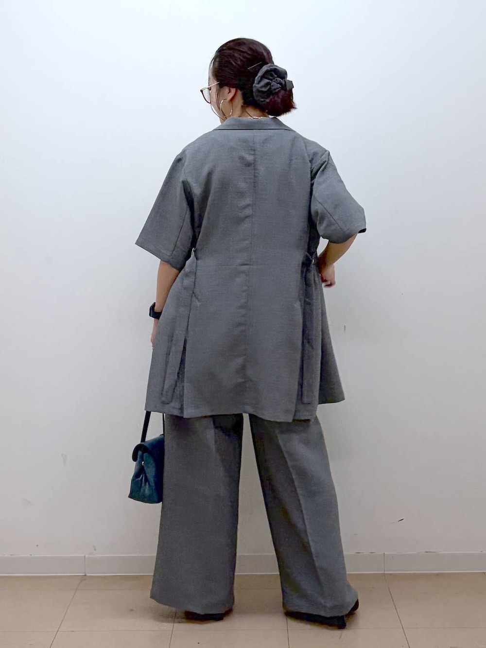 ホワイト系のTシャツ/カットソー、グレー系のスラックス、ブラック系のサンダルを着用したレディースの夏コーディネートの6枚目の写真