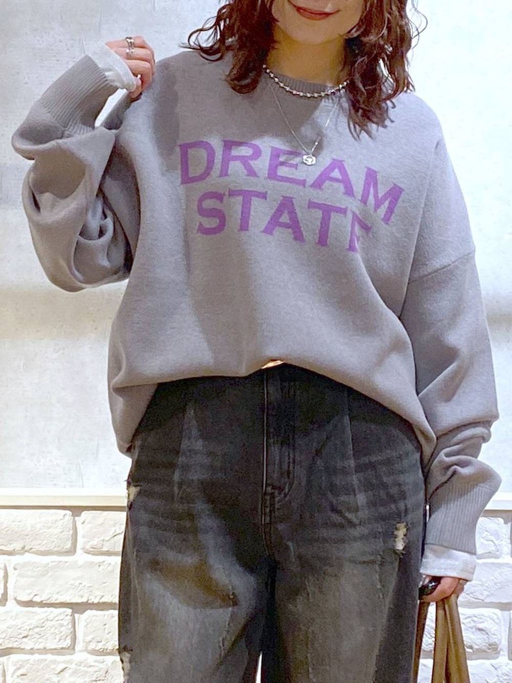 ベージュ系のスニーカー、イエロー系のボストンバッグ、ブラック系のデニムパンツを着用したレディースの秋コーディネートの2枚目の写真