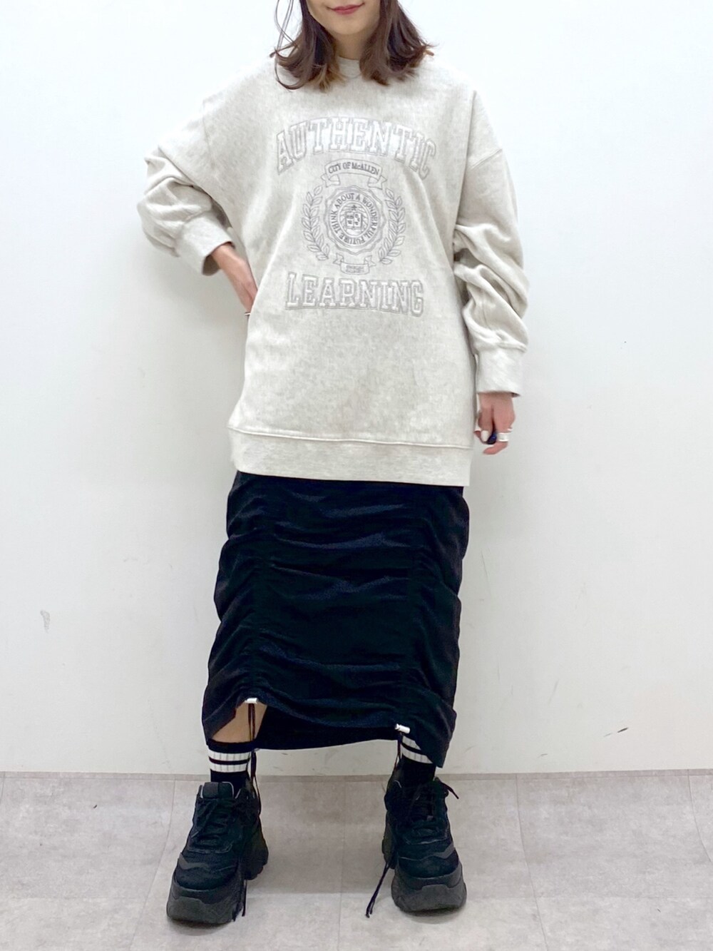 ベージュ系のスウェット、ブラック系のワンピース、ブラック系のスニーカーを着用したレディースの冬コーディネートの6枚目の写真