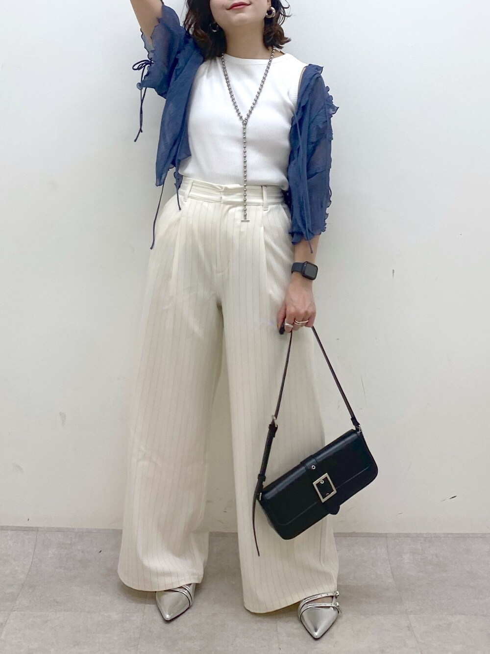 ホワイト系のスラックス、ブラック系のハンドバッグ、シルバー系のパンプスを着用したレディースの夏コーディネートの3枚目の写真