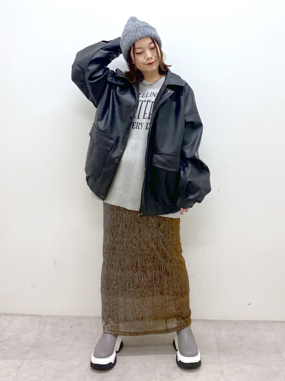 グレー系のニット/セーター、ブラック系のブルゾン、ゴールド系のスカートを着用したレディースの秋コーディネートの4枚目の写真