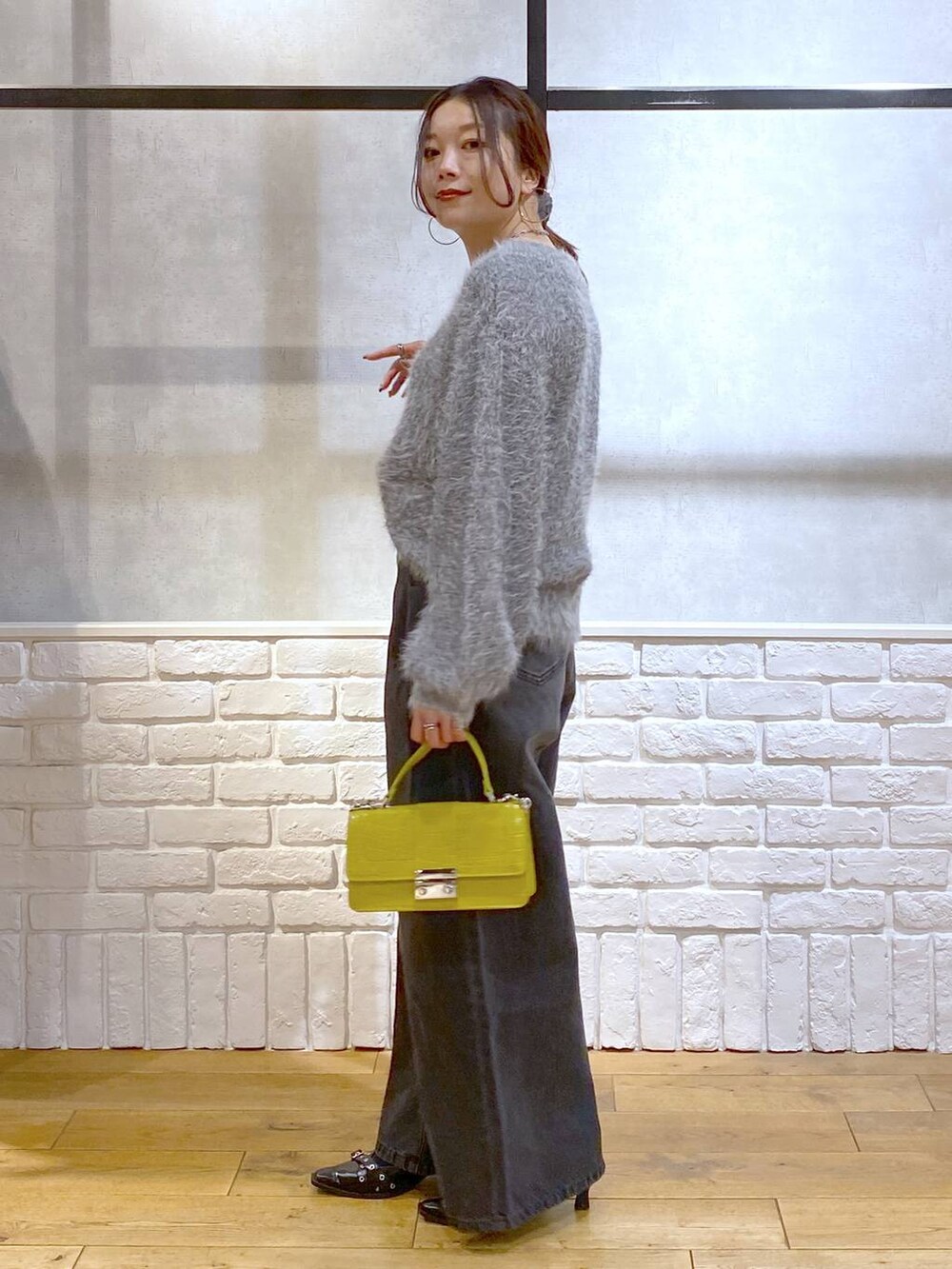 ブラック系のデニムパンツ、イエロー系のハンドバッグ、ブラック系のパンプスを着用したレディースの秋コーディネートの5枚目の写真