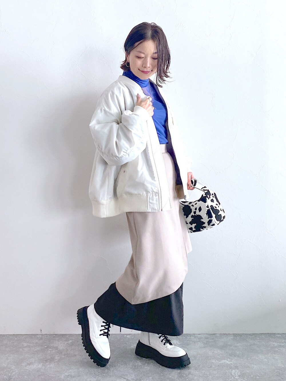 ホワイト系のMA-1、ベージュ系のスカート、ホワイト系のブーツを着用したレディースの夏コーディネートの2枚目の写真