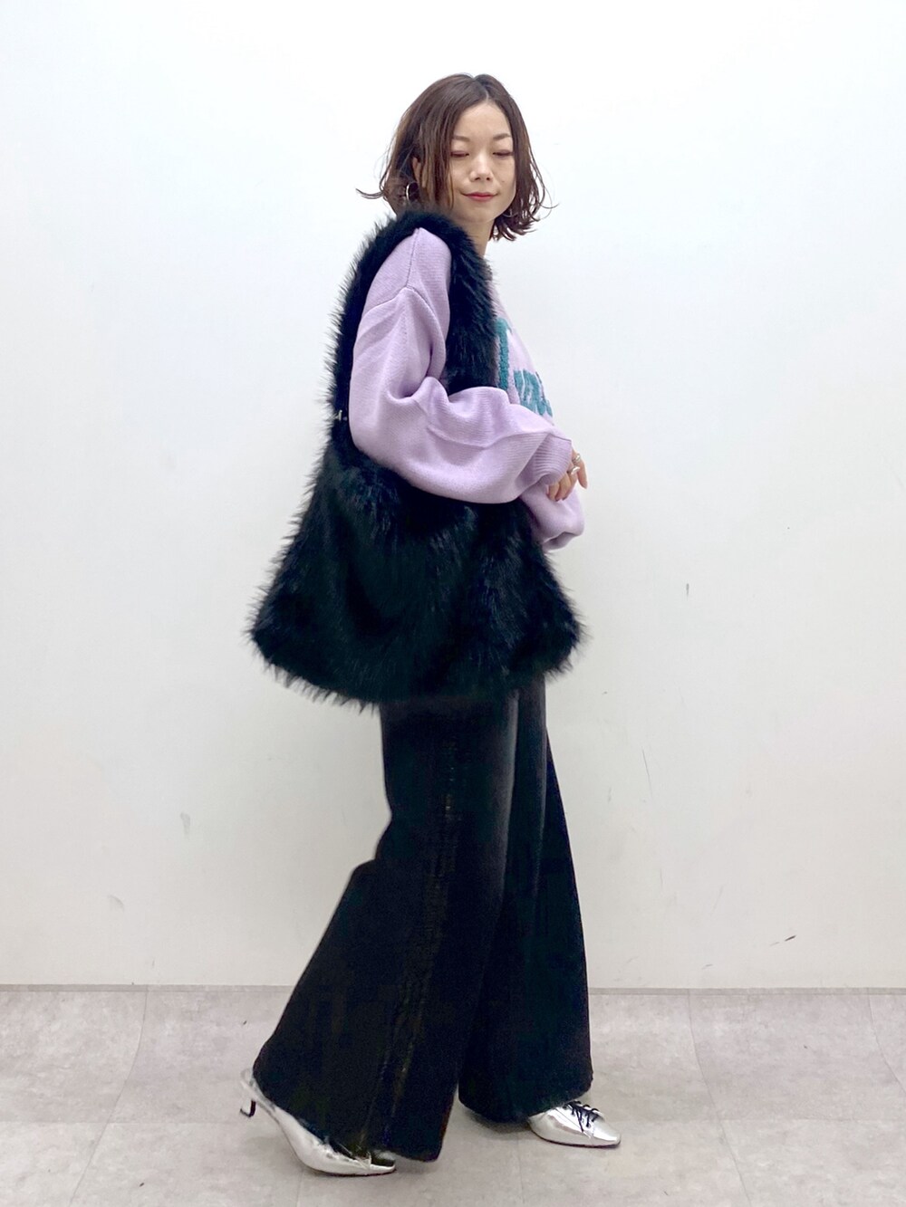 パープル系のニット/セーター、ブラック系のデニムパンツ、シルバー系のパンプスを着用したレディースの秋コーディネートの7枚目の写真