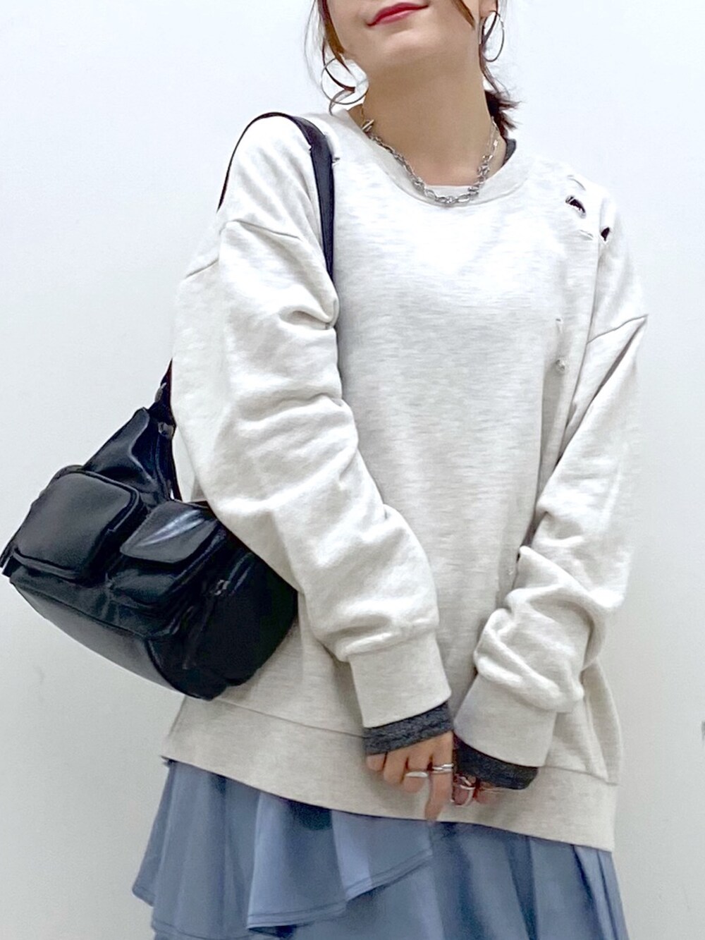 ブラック系のショルダーバッグ、ブルー系のスカート、グレー系のブーツを着用したレディースの秋コーディネートの2枚目の写真