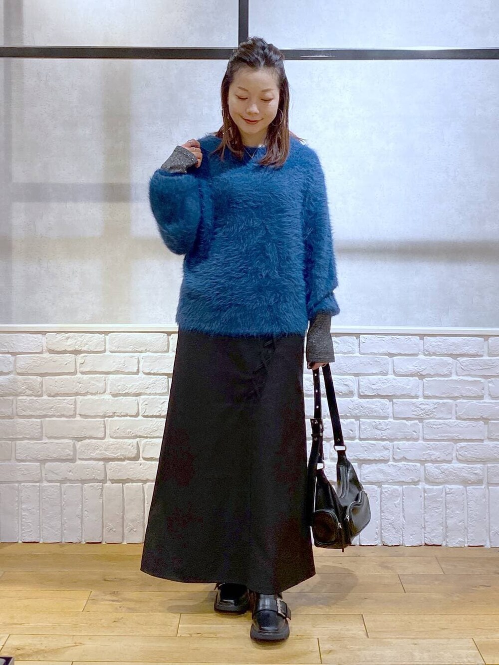 シルバー系のTシャツ/カットソー、ブラック系のブーツ、ブルー系のニット/セーターを着用したレディースの冬コーディネートの4枚目の写真