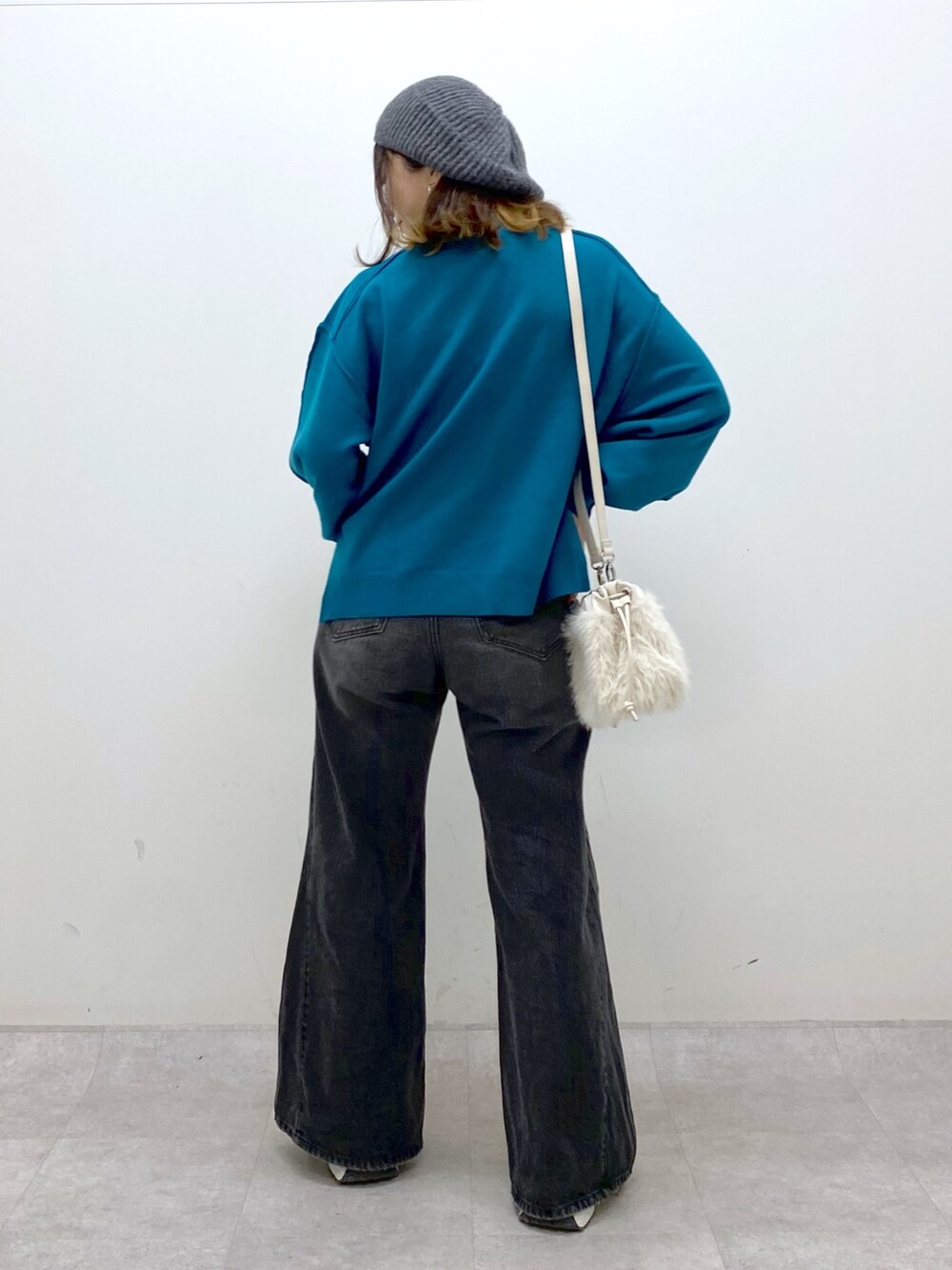 ブラック系のデニムパンツ、ホワイト系のショルダーバッグ、ブルー系のニット/セーターを着用したレディースの秋コーディネートの5枚目の写真