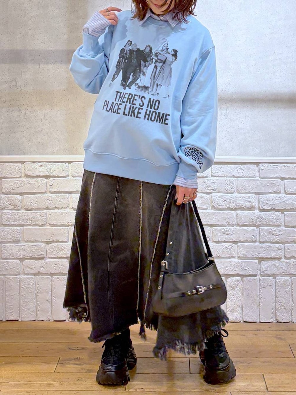 ブラック系のスニーカー、ブラック系のハンドバッグ、ブラック系のデニムスカートを着用したレディースの春コーディネートの3枚目の写真