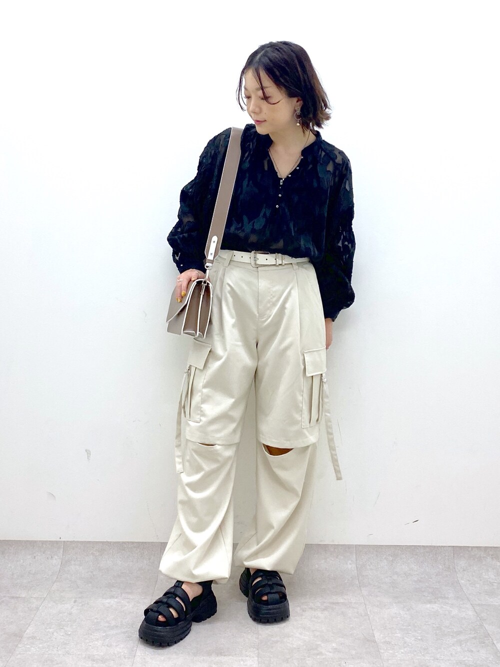 グレー系のパンツ、ブラック系のサンダル、ブラウン系のショルダーバッグを着用したレディースの春コーディネートの5枚目の写真