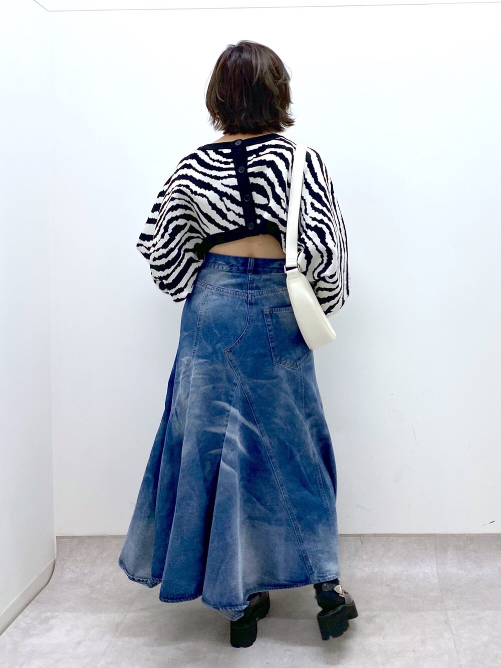 ブルー系のスカート、ブラック系のトップス、ホワイト系のショルダーバッグを着用したレディースの冬コーディネートの4枚目の写真